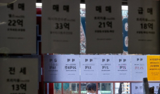 한 시민이 부동산 매물 시세가 게재된 부동산공인중개업소 매물정보 게시판 앞을 지나가고 있디.   연합뉴스